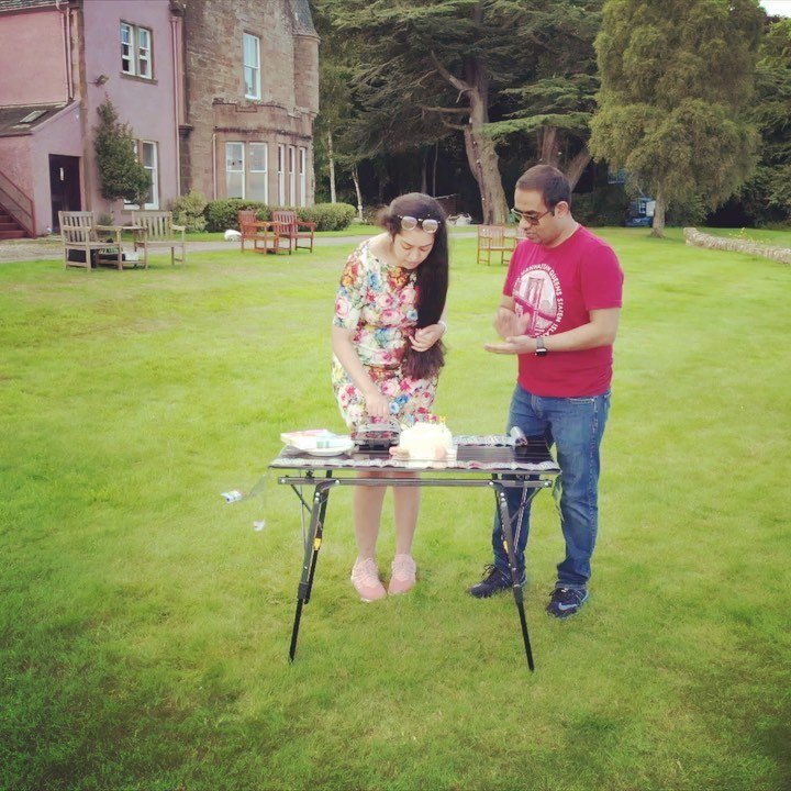 Meenu and Praddy at a small table on the lawn in front of Bunchrew House