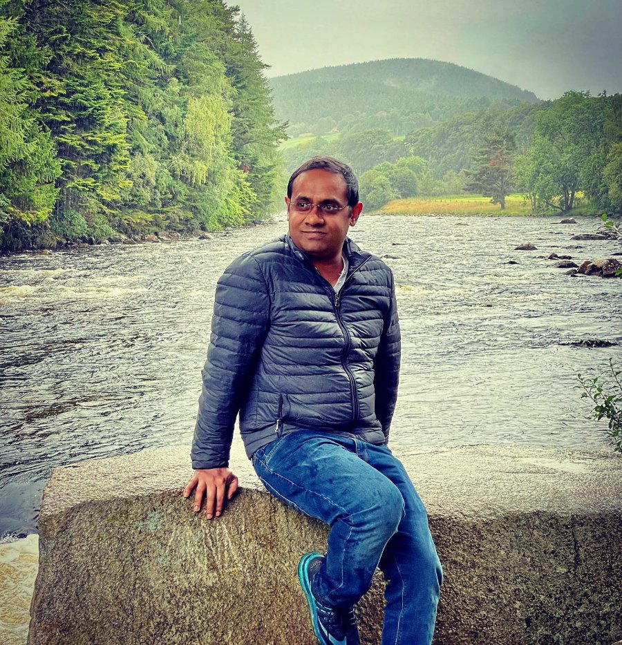 Praddy sitting by a wide, shallow river on the Balmoral estate