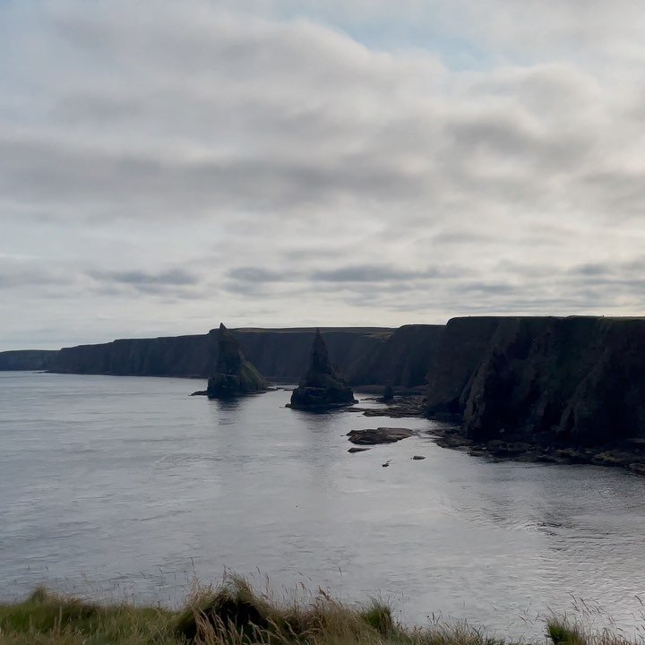 The Duncansby Stacks rising from the sea beside a long line of dark cliffs