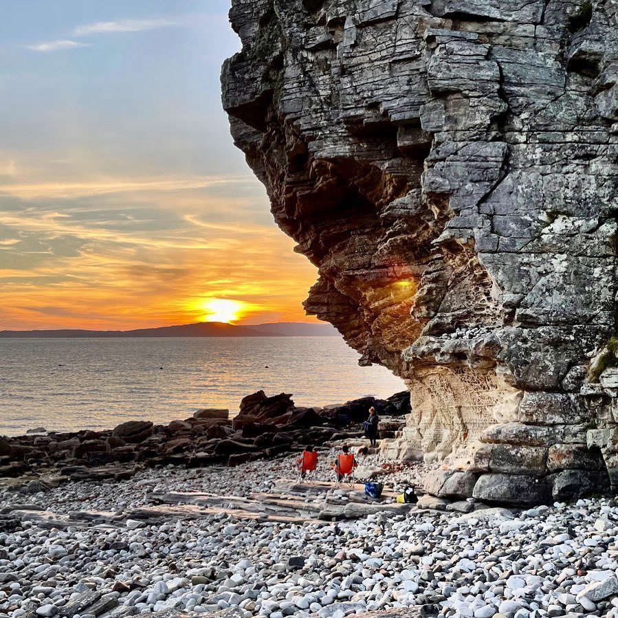 The sun setting over the sea at Elgol beside a tall overhanging rock