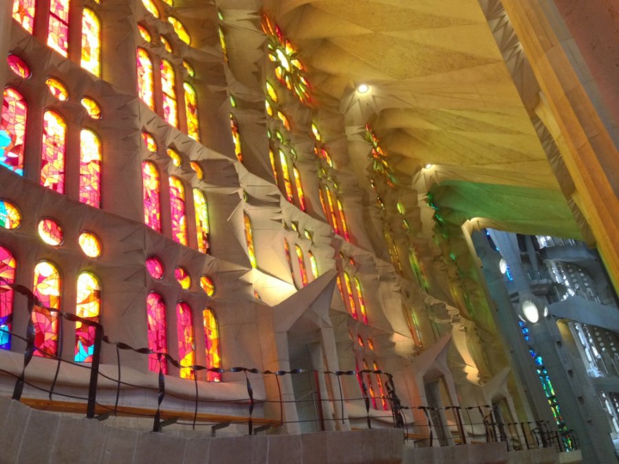 Stained glass throwing red, orange and green light across the vaults inside the Sagrada Família