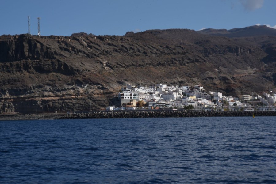 White houses at the foot of brown cliffs, seen from the boat