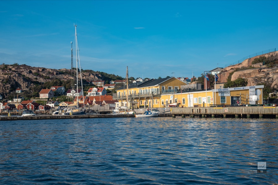 Yellow harbour buildings and sailing boats below a bare granite hill