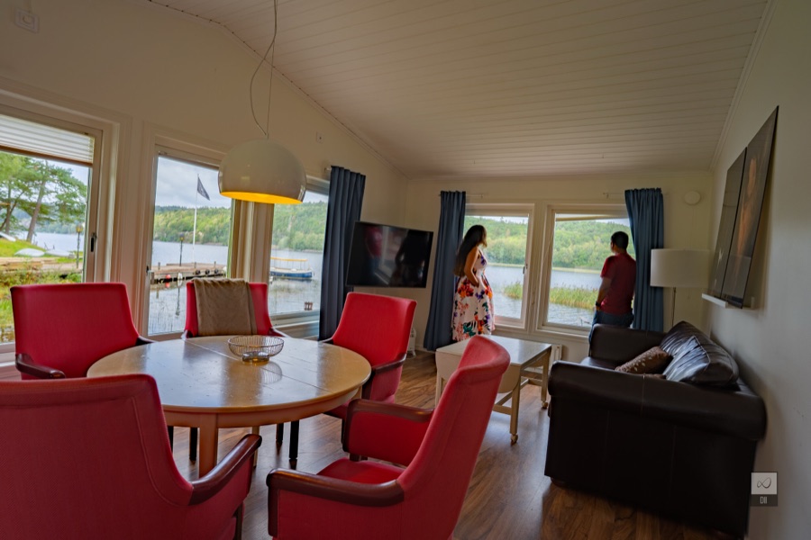 Meenu and Praddy at the window of our cabin, looking out at the lake past red dining chairs