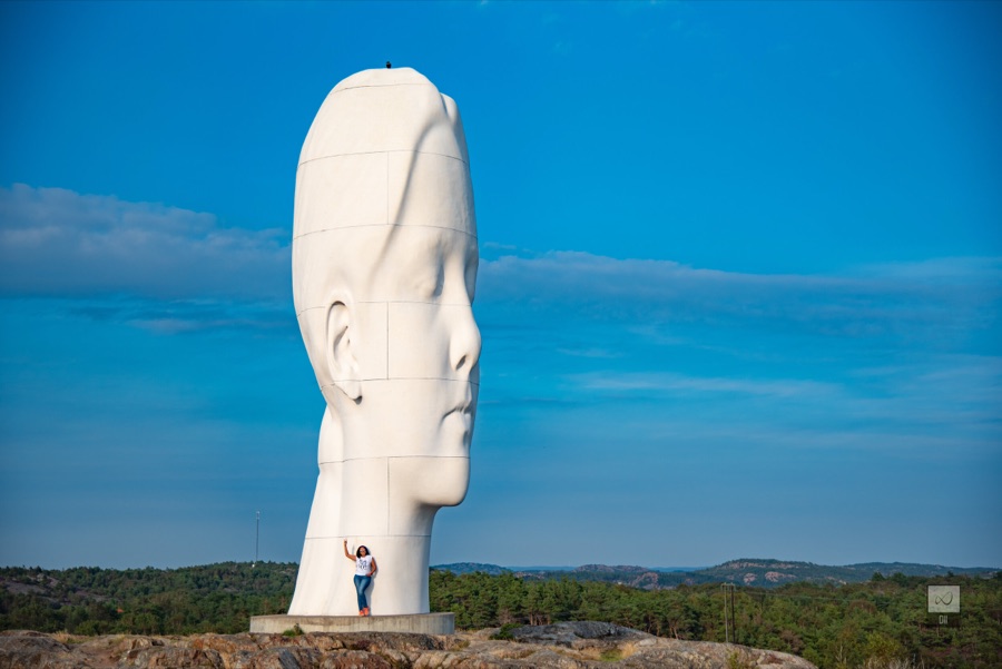 Meenu waving at the foot of Anna, tiny beside the sculpture