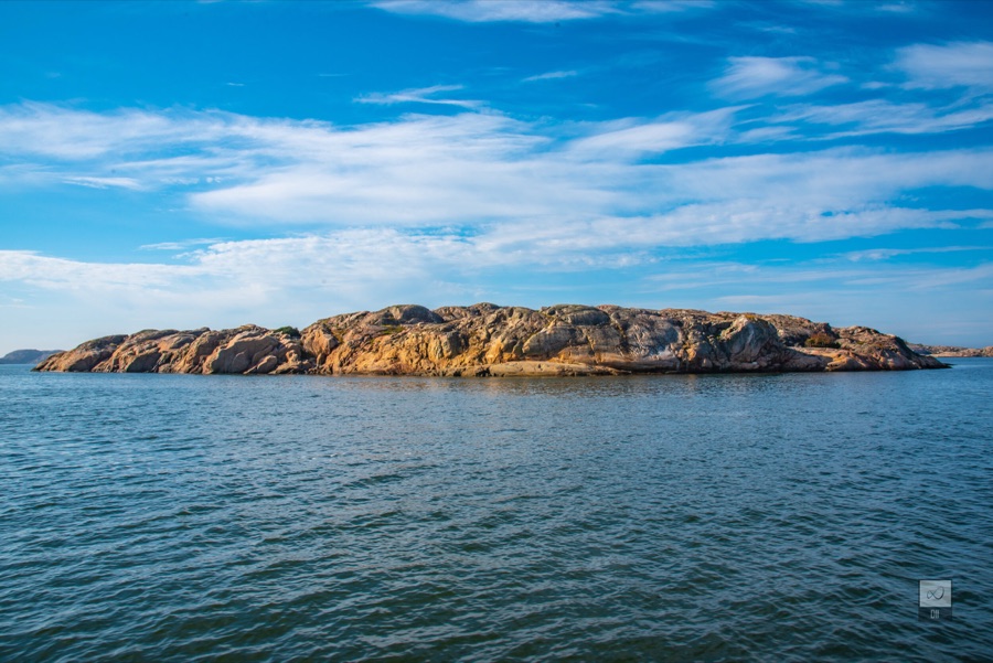 A low, rounded island of bare granite in a blue sea