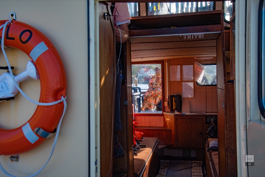 An orange lifebuoy beside the open door to the boat's wooden cabin