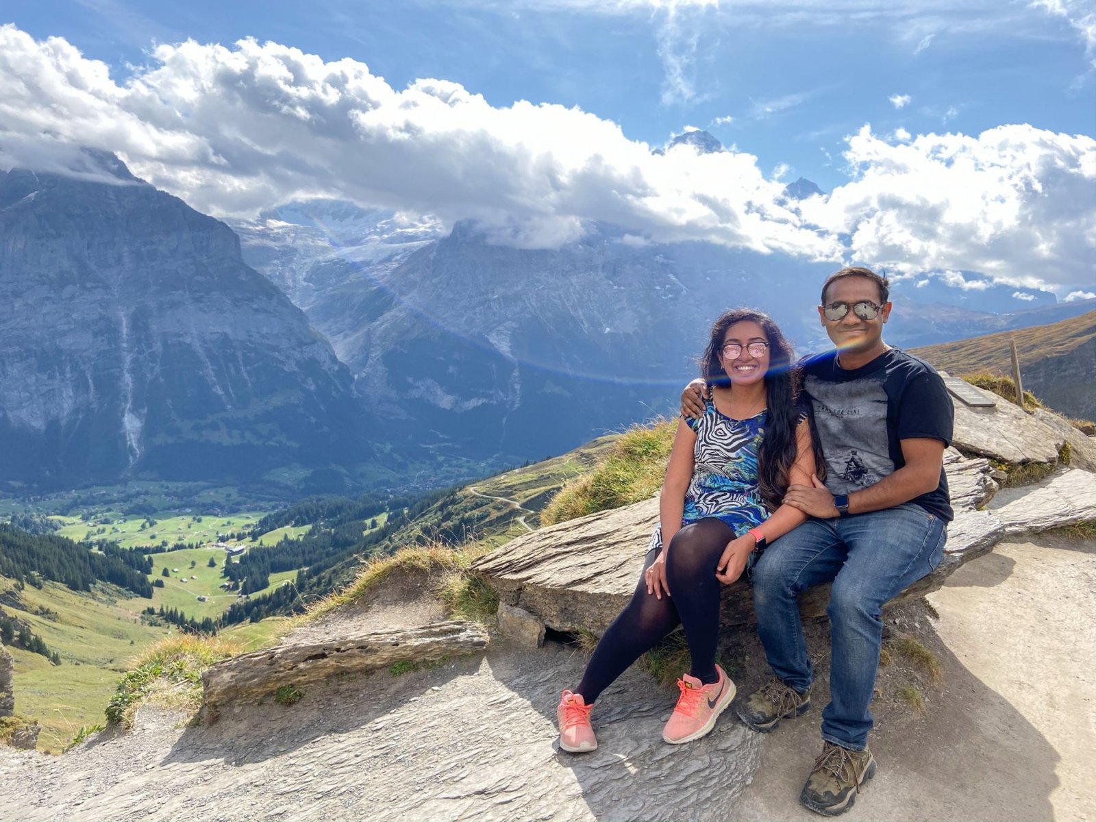 Meenu and Praddy sitting on the rocks above the Grindelwald valley, with cloud along the peaks