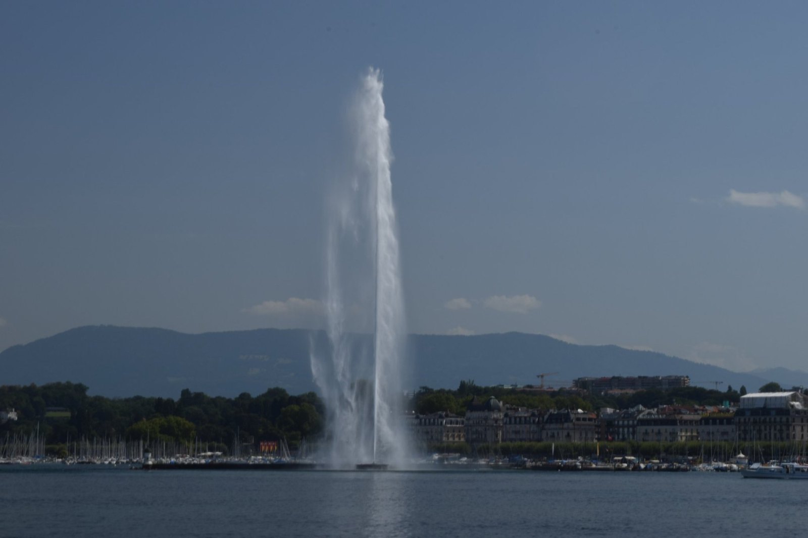 The Jet d'Eau shooting high above Lake Geneva, with hills beyond the far shore