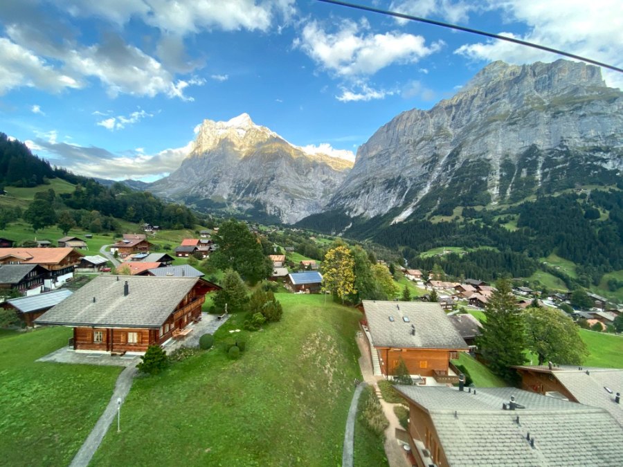 Grindelwald's chalets and green meadows seen from the gondola, with the mountains behind