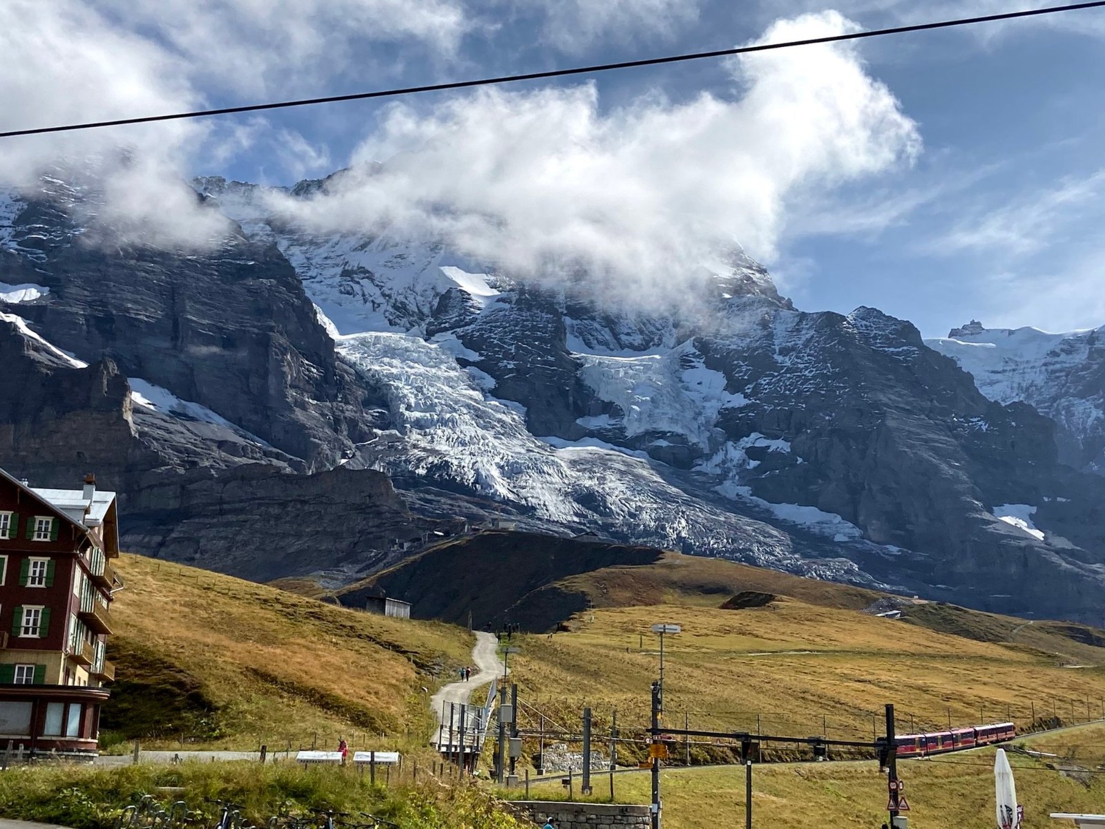 Kleine Scheidegg's hotel below glacier-hung peaks, with a red Jungfrau Railway train on the line
