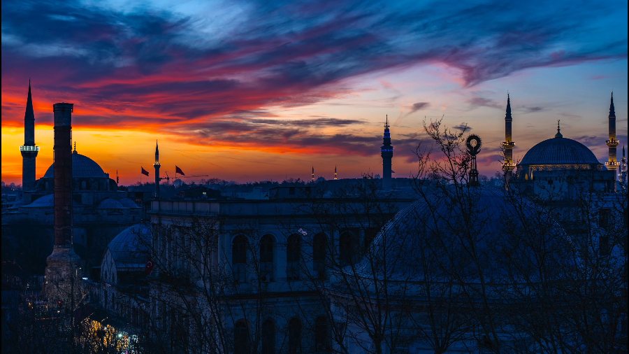 Istanbul's domes and minarets in silhouette under a red and orange sunset