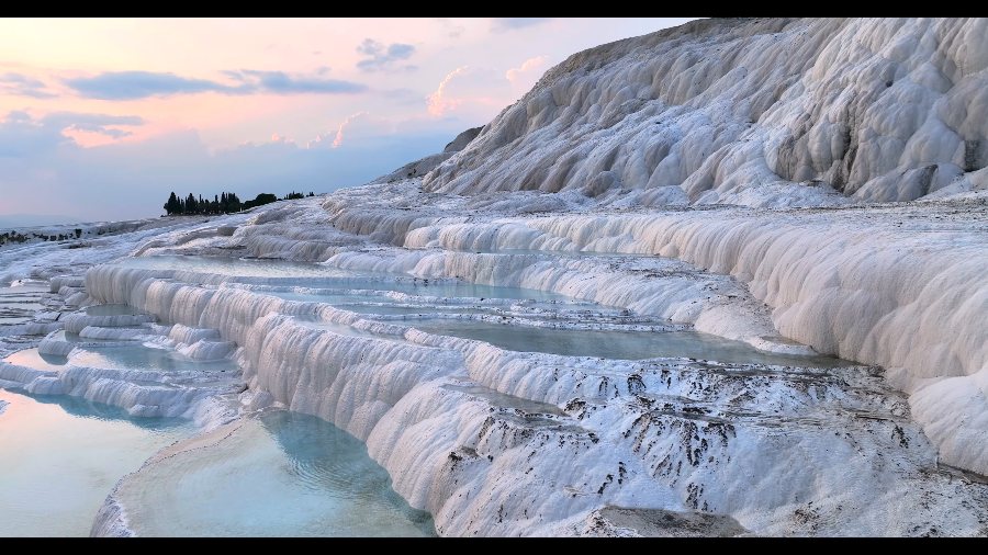 Pamukkale's white terraces and pools under a pink sunset sky