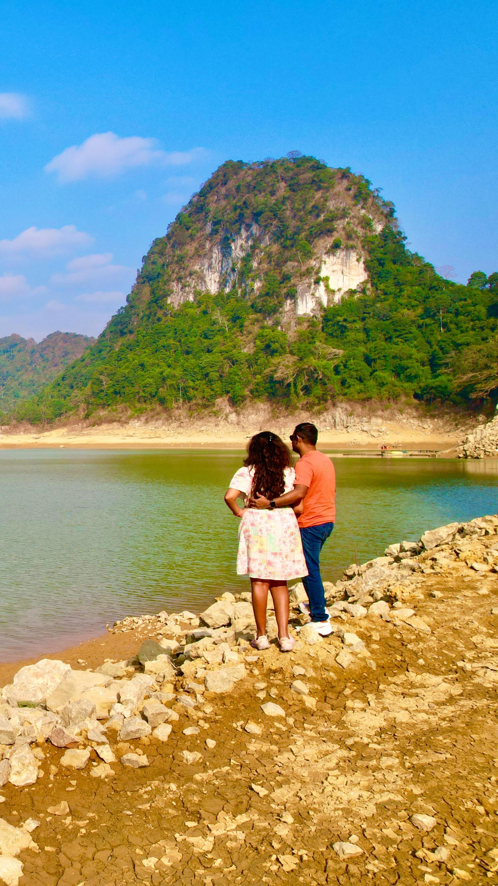 The two of us at the edge of Thang Hen lake, below a green limestone hill
