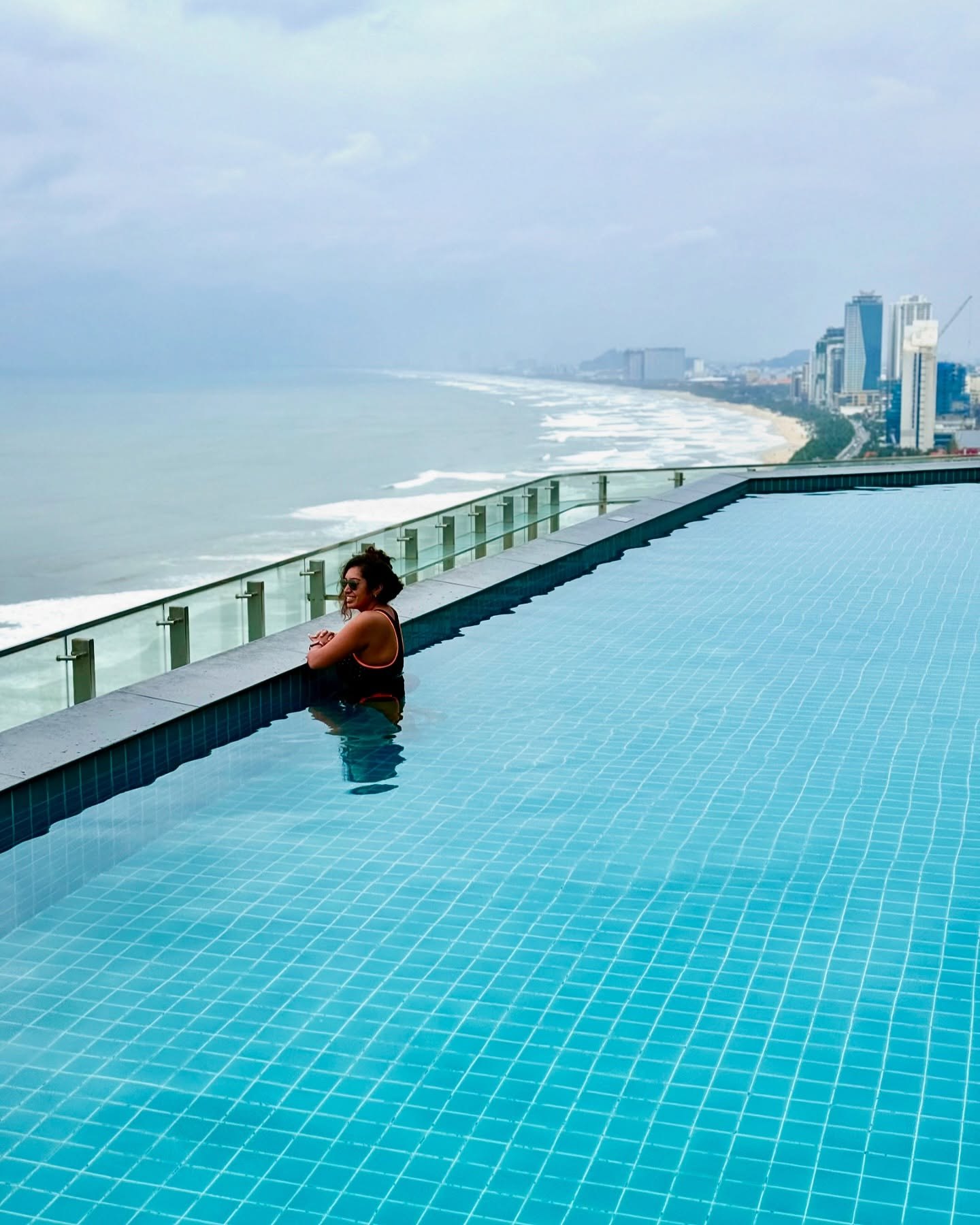 Meenu in the Radisson's rooftop infinity pool, with Đà Nẵng's beach curving away to the city