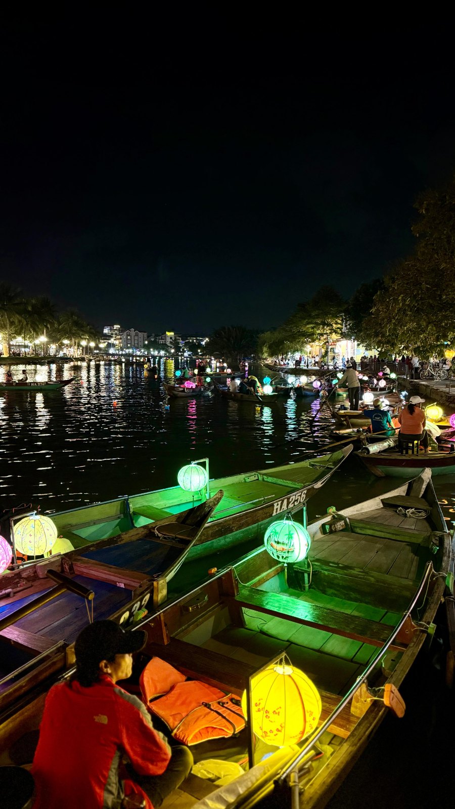Hội An at night from above, the old town's lights across the river and lantern boats below
