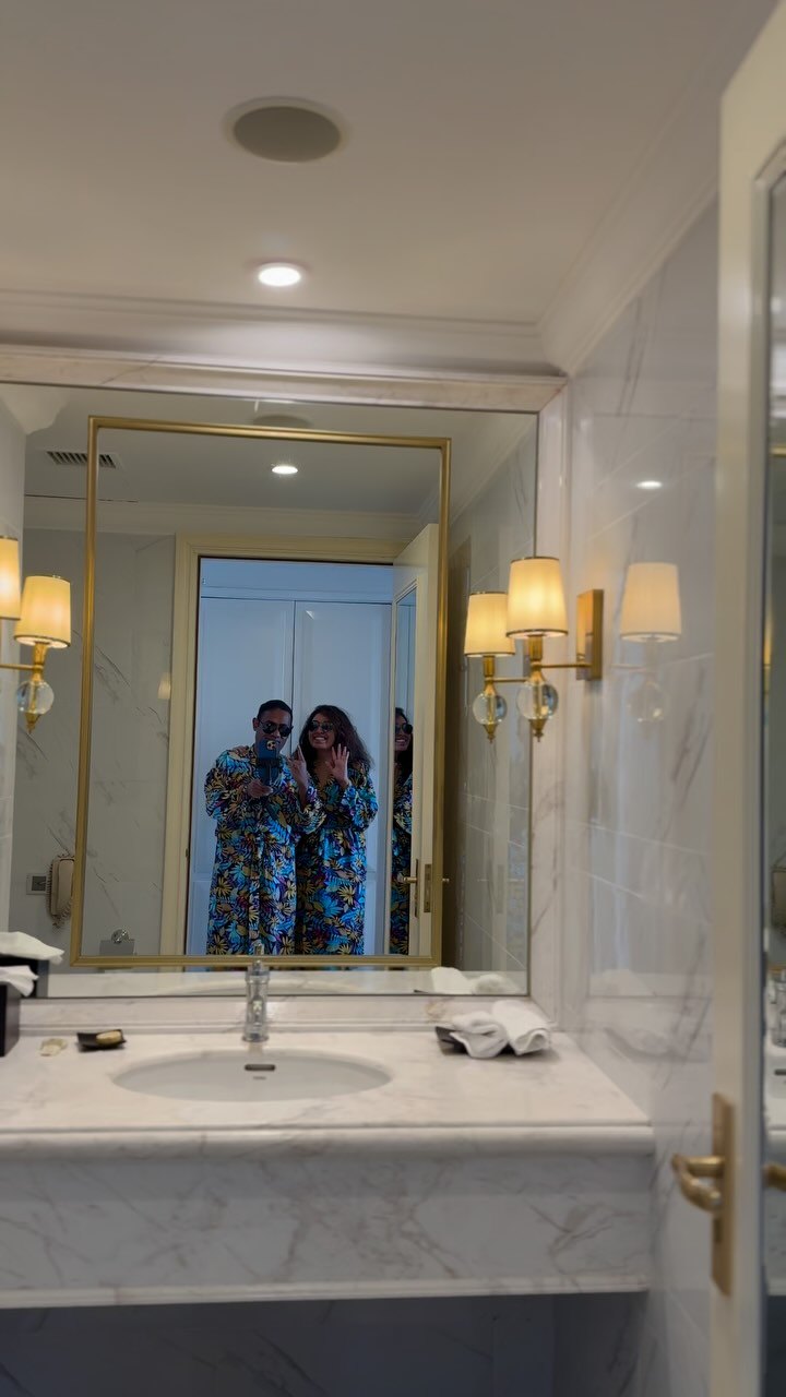 Our reflection in the bathroom mirror of our suite at the Vinpearl, between two wall lamps