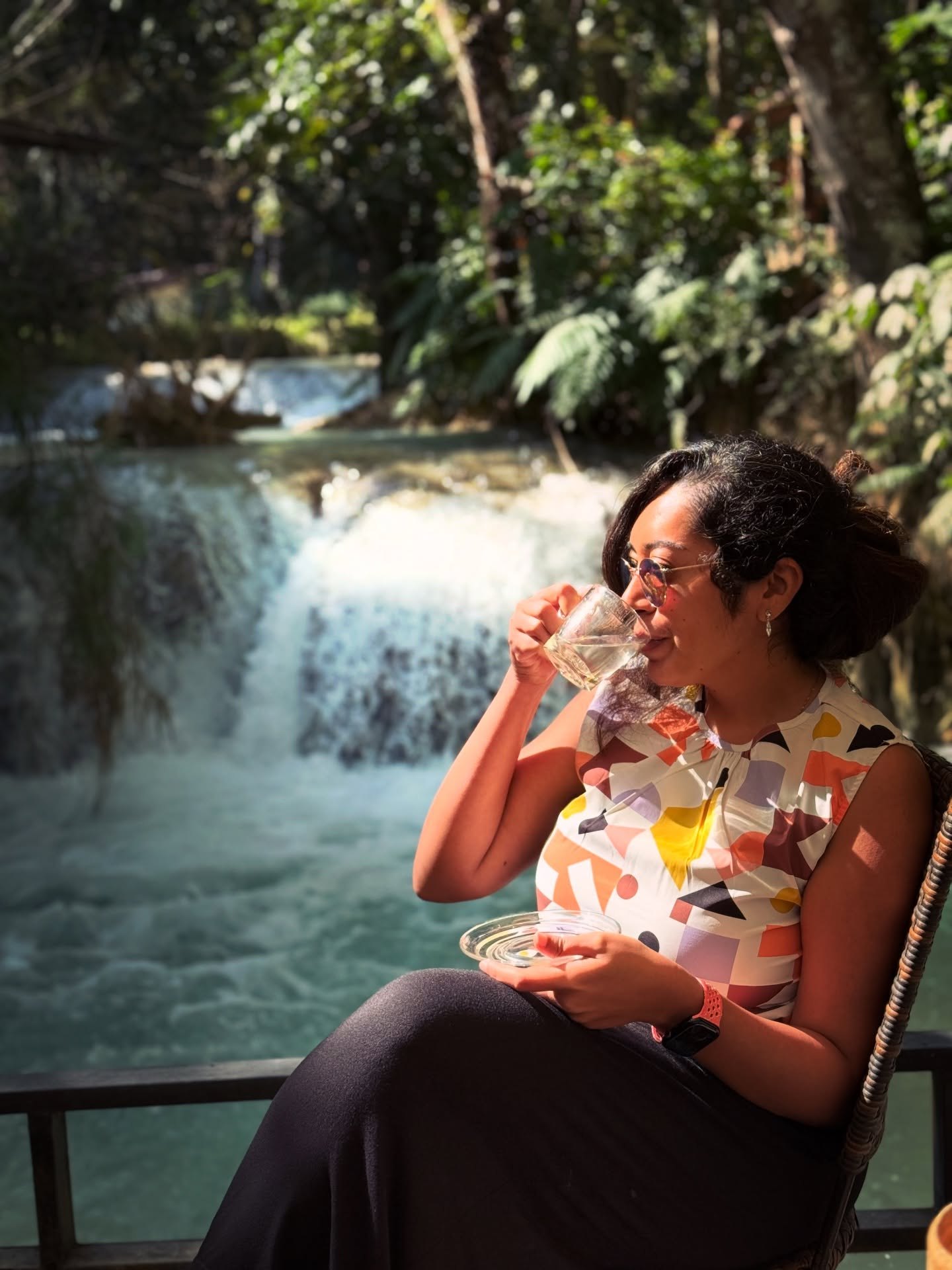 Meenu sipping ginger tea on a deck beside the Kuang Si falls