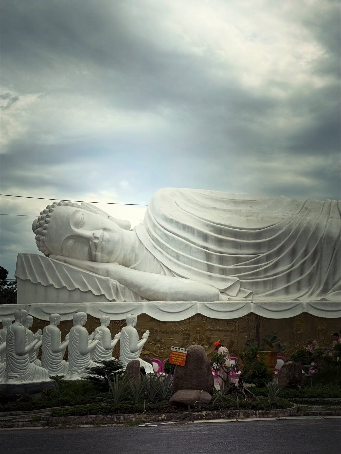 A long white reclining Buddha under a stormy sky at Chùa Gò Kén in Tây Ninh