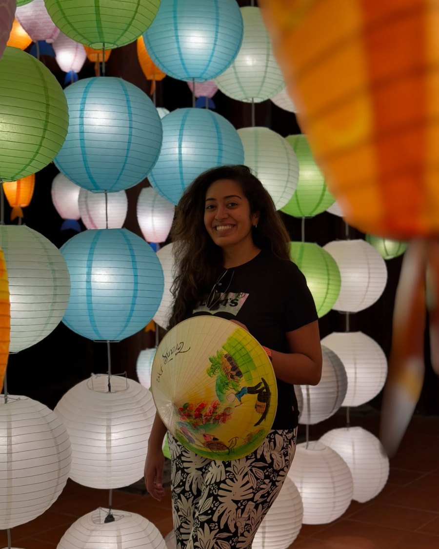 Meenu smiling among rows of glowing paper lanterns at Tràng An