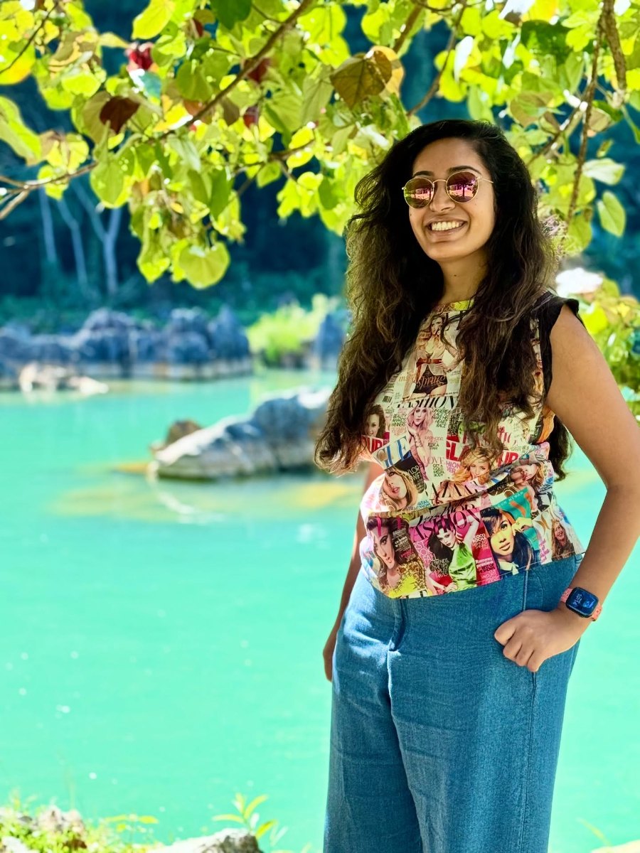 Meenu under the trees beside the turquoise water of a blue lagoon at Vang Vieng
